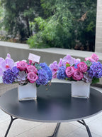 Arreglo floral con orquídea y suculentas en jarrón cuadrado de vidrio.